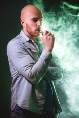 Men with beard  in sunglasses vaping and releases a cloud of vapor.Men with beard  in sunglasses...
