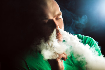 Men with beard  in sunglasses vaping and releases a cloud of vapor.Men with beard  in sunglasses...