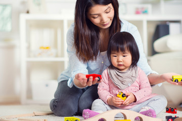 Pretty happy japanese mother play with her little toddler daught