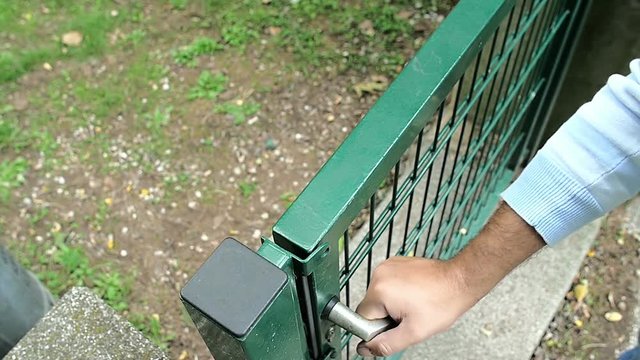 hand of man opens the gate to a garden