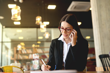 Young business woman having a phone conversation at cafeteria.