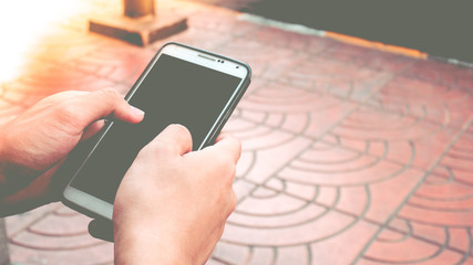 Asian young boy holding black blank screen smart phone on street. Black blank empty screen for text and logo.