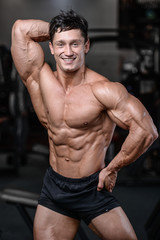 Fototapeta premium Handsome bodybuilder training in the gym sexy man lift dumbbells