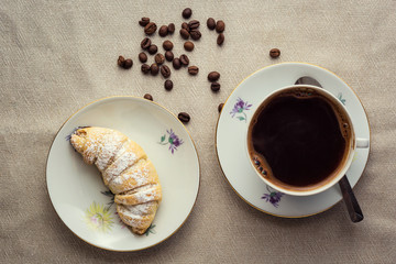 delicious coffee with croissant,a cup of coffee and croissants with coffee beans and cinnamon sticks,breakfast with cup of coffee, croissants and chocolate