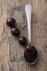 Close-up of cherries in a silver spoon on brown background