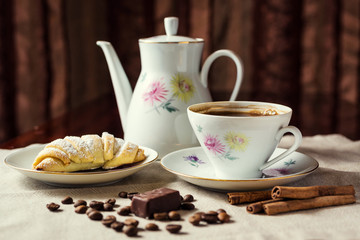 delicious coffee with croissant,a cup of coffee and croissants with coffee beans and cinnamon sticks,breakfast with cup of coffee, croissants and chocolate