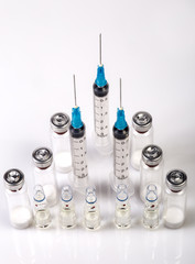 Three medical syringes, vials with dry human hormone powder and ampules with saline. Syringes staying with bare needles, all medical bottles are staying. Sport doping in bodybuilding. Macro image.

