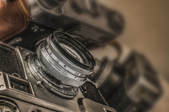 Close up view of old Russian analog film camera with vintage look. On the camera, there can be seen aperture ring, focusing ring, lens, filter thread. In background is another old camera with lens