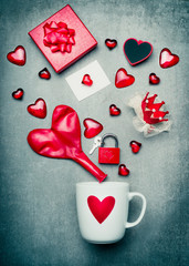 Cup with heart symbol and red Valentines day decoration with gift box, greeting card, lock and key, crown and balloon in heart form.