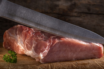 Cutting raw pork muscle with knife over wood - Powered by Adobe