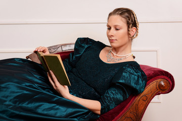 victorian woman laying on couch reading book