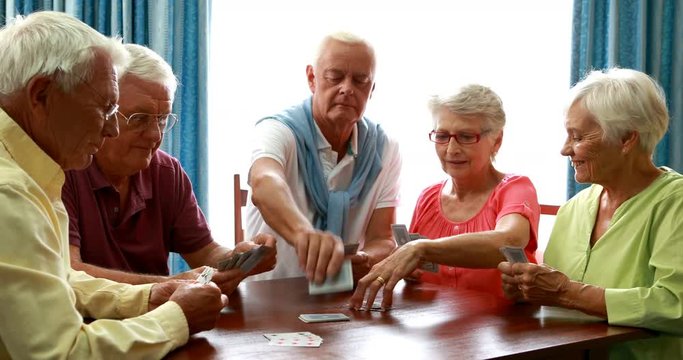 Senior friends playing cards in living room
