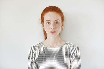 Portrait of young tender redhead teenage girl with healthy freckled skin wearing striped top...