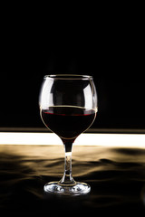 glass of red wine on a black background backlit