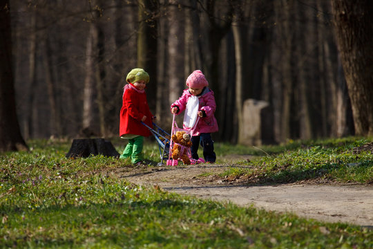 kid girls playing mother daughter game in the spring city park