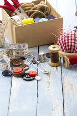 tools tailor spools threads buttons needle sewing blue white rusty vintage wooden background
