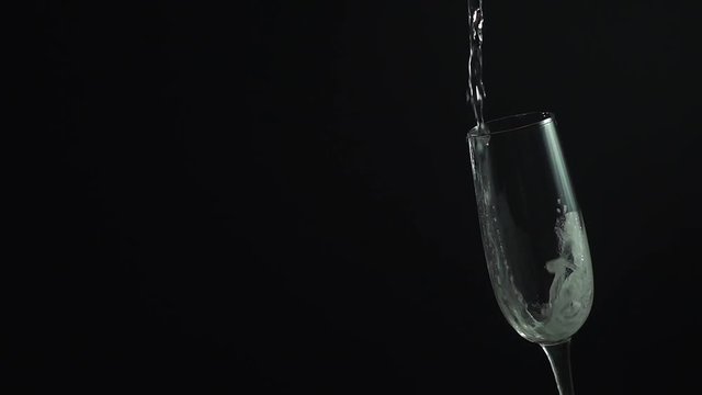 Champagne pouring from bottle into glass on black, slow motion hd video