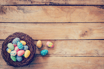 Colorful easter egg in the nest on wood background with space