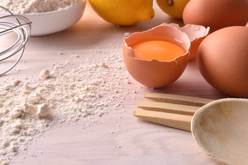 Fresh eggs flour and lemon with utensils on bench elevated