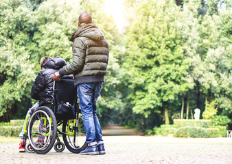 Carer man with young disabled with handicap on wheelchair 