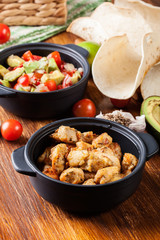 Ingredients ready for preparing chicken tacos with salsa made from avocado, tomatoes, and chilli peppers