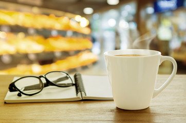 Cup of coffee and note book on wooden table. Coffee break in mor