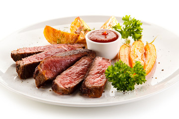 Grilled steak, baked potatoes and grilled carrots on white background 