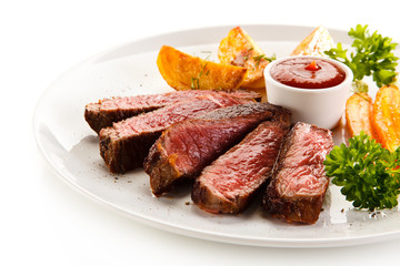 Grilled steak, baked potatoes and grilled carrots on white background 