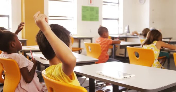 School kids raising hand in classroom