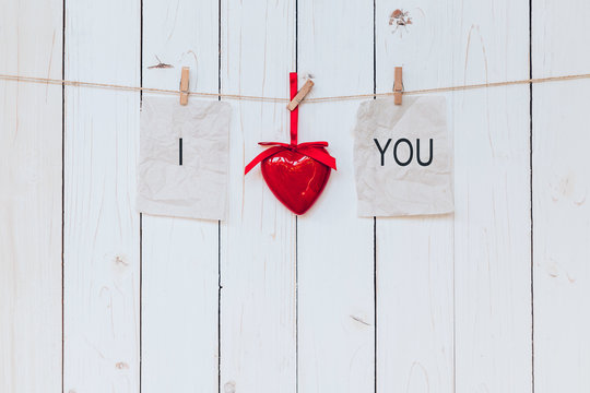 Red heart and old paper with text I LOVE YOU hanging at clothesl