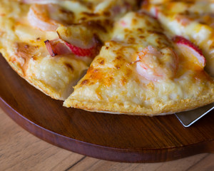 close up of delicious fresh pizza with seafood on wooden table.
