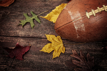 Old worn football with autumn leaves