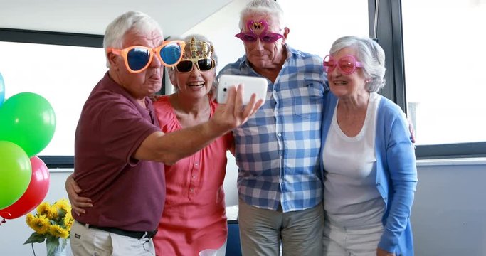 Senior citizens taking selfie on mobile phone during birthday party
