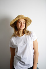 Smiling young woman standing in a straw hat