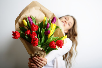 Smiling girl peeping from behind a bouquet of flowers. Concept M