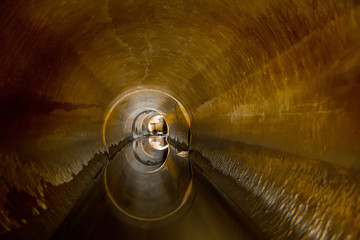 Flooded round sewer tunnel is reflecting in water