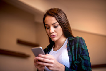Fototapeta premium Beautiful young woman typing a message on her smartphone. 