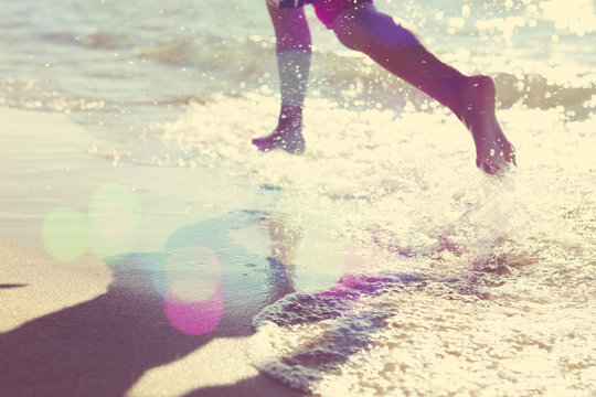 Child Running At The Beach, Runner Has Motion Blur. Focus On San