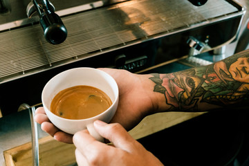 Fototapeta na wymiar Baristas are coffee,by tattooed barista arm