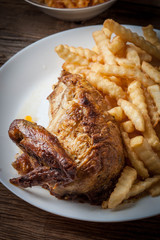 Roasted chicken with french fries on a plate.