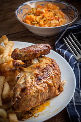 Roasted chicken with french fries on a plate.