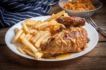 Roasted chicken with french fries on a plate.