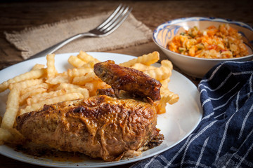 Roasted chicken with french fries on a plate.