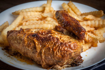 Roasted chicken with french fries on a plate.