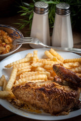 Roasted chicken with french fries on a plate.