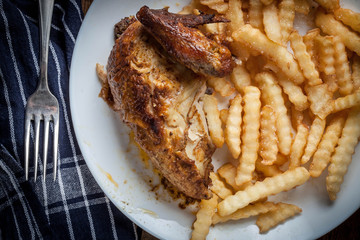 Roasted chicken with french fries on a plate.
