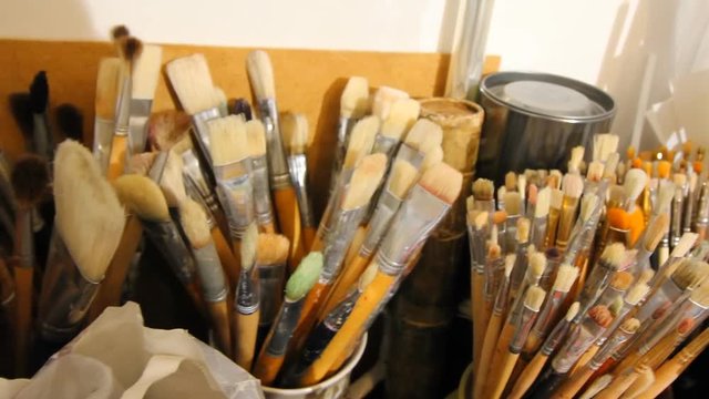 Paintbrushes on Art workroom background. Oil painting material close up. Pan.