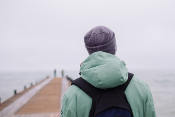man on wooden pier on the background of sea. Rear view
