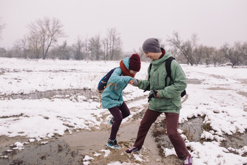 young woman and a man pass a puddle during the spring snow melt