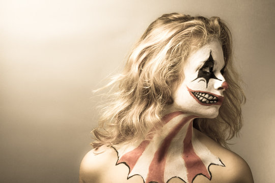 Portrait d'une jeune fille blonde maquillée en joker de profil, la tête tournée vers la gauche, avec filtre sépia